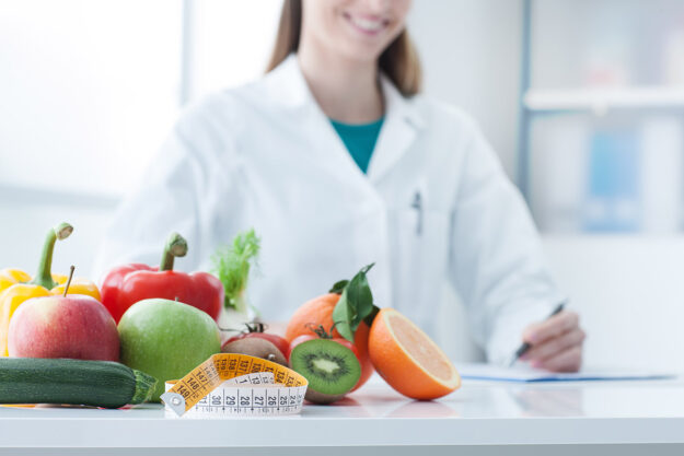 How Does Medical Weight Loss Work Doctor smiles next to healthy fruits and vegetables as she is asked "what is medical weight loss?"