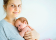 Woman holds her baby after talking to a friend about how to optimize hormones