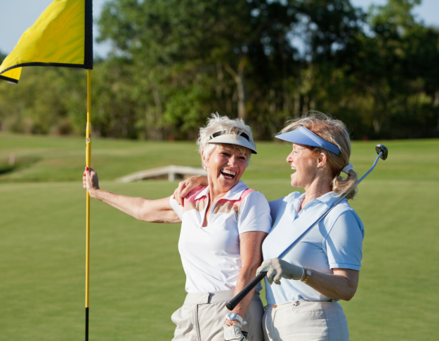 Active Women Golfing – Regenerative Medicine Benefits Two smiling, active older women on a golf course holding a flag and golf club, representing the mobility and performance benefits of regenerative medicine.
