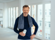 A fit, confident middle-aged man smiling with a gym towel and water bottle, representing male vitality and regenerative longevity treatments.