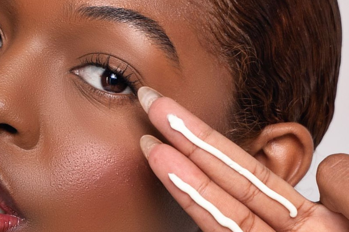 Woman with glowing skin applying sunscreen