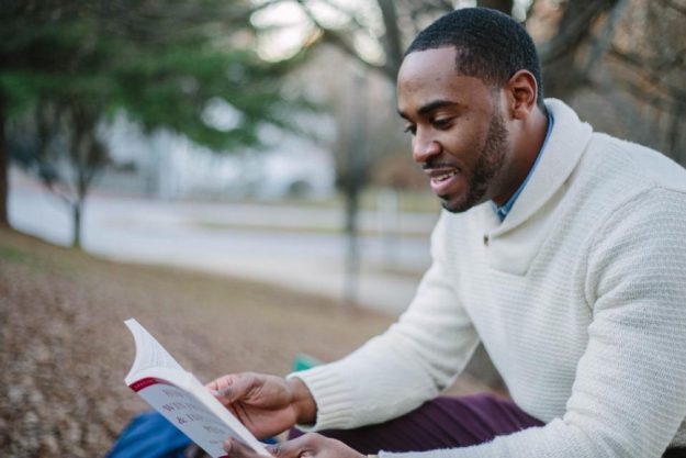 Man sitting outdoors reading, taking time to consider his options